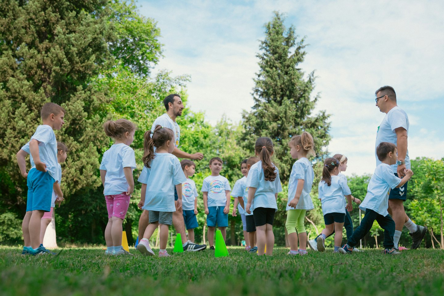 Zwei Lehrerinnen leiten eine Gruppe von Kindern bei einem Spiel im Freien.